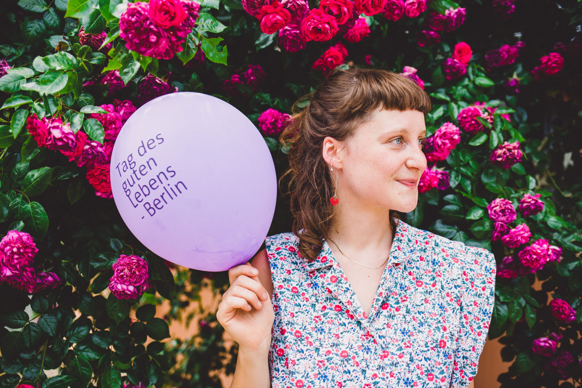 Frau mit Luftballon vor Strauch