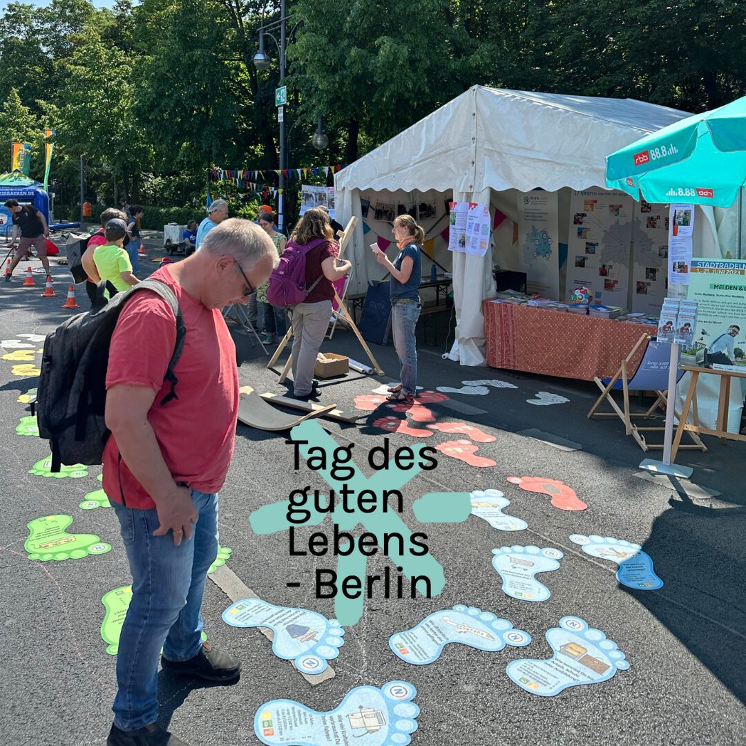 Besucher beim Umweltfestival betrachten unseren Stand und die SDG-Fussabdrücke